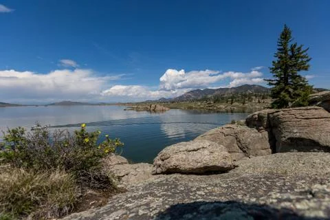 Dramatic sky and clouds reflecting over a large mountain lake with calm waters Stock Photos