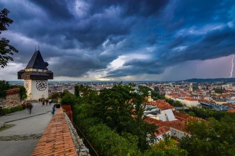 Dramatic sky and lightning storm over the city of Graz and the famous clock t Stock Photos