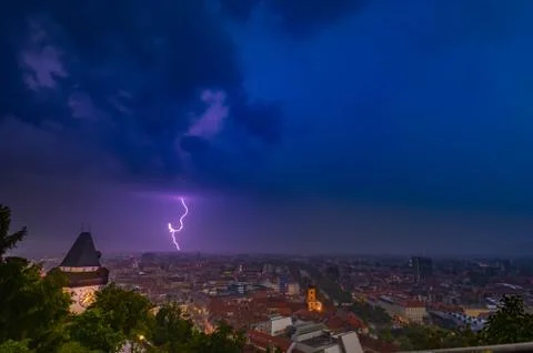 Dramatic sky and lightning storm over the city of Graz and the famous clock t Stock Photos