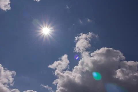Dramatic sky background with bright sun rays and cumulus clouds on sunny day Foto stock