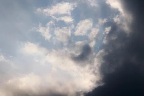 Dramatic sky background with bright sunlit clouds and a dark approaching stor Stock Photos