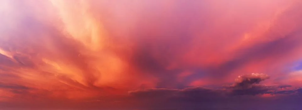 Dramatic sky background with orange and purple clouds at sunset. Stock Photos