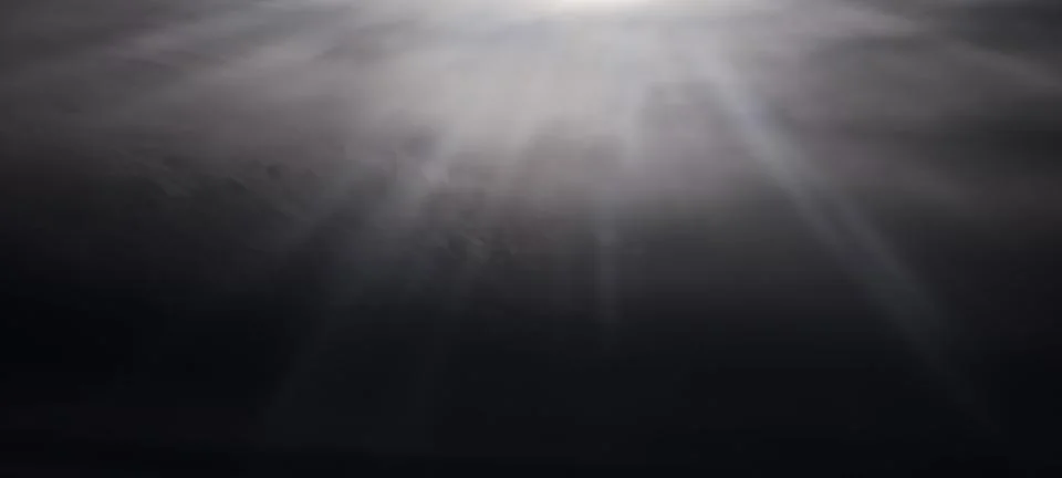 A dramatic sky with beams of sunlight piercing through thick clouds Stock Photos