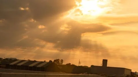 Dramatic sky between clouds in the late afternoon and the silhouette of a fac Stock Photos