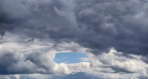 Dramatic sky with a break in dark storm clouds revealing blue sky 写真素材