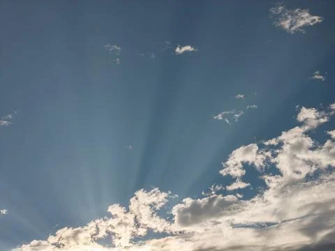 Dramatic sky with bright sun rays fanning upward through a bank of white and Фото