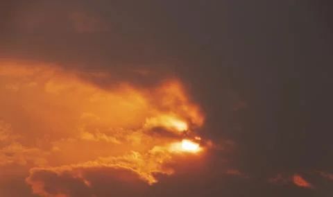 Dramatic sky with bright sun shining through the dark clouds. Stock Photos