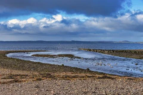Dramatic sky casts deep blue and white across the shore Stock Photos