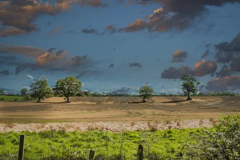 Dramatic sky casts warm hues over open farmland Stock Photos