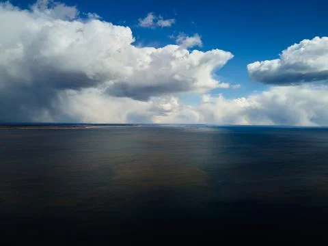 Dramatic sky with clouds above the blue lake or river before the rain. Stock Photos