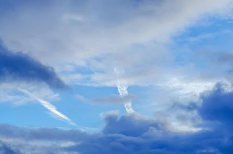 Dramatic sky with clouds and contrails on a bright, sunny day Stock Photos