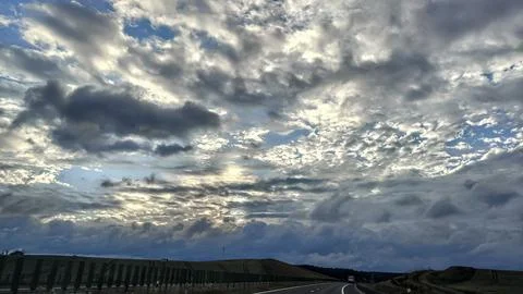 Dramatic sky with clouds over a highway and rolling hills at sunset Foto stock