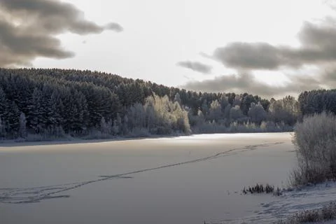 Dramatic sky with clouds over the winter forest and lake. 스톡 사진