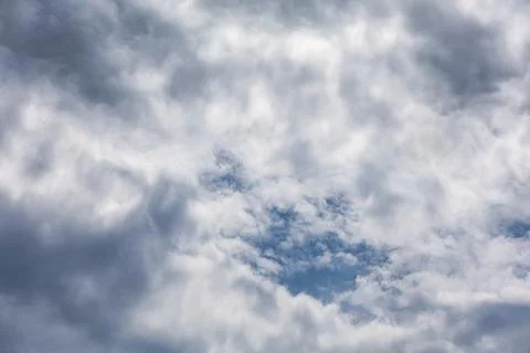Dramatic sky with dark and light clouds revealing patches of blue sky 스톡 사진