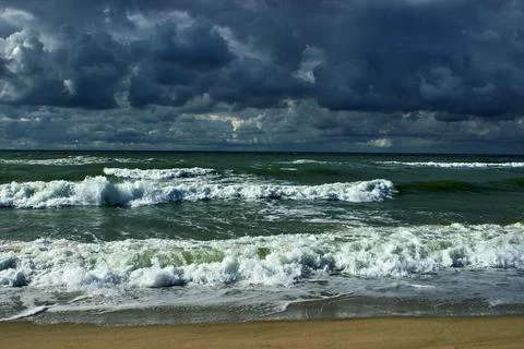 Dramatic sky with dark clouds and stormy sea with rolling waves Stock Photos