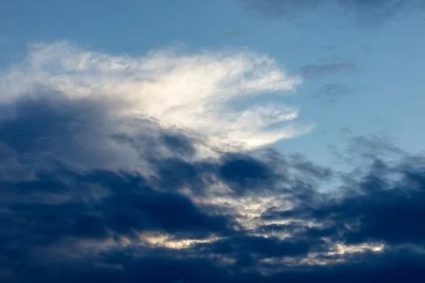 Dramatic sky with dark clouds and bright illuminated wisps 库存照片