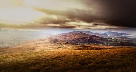 A dramatic sky with dark clouds hangs over a vast valley Stock Photos
