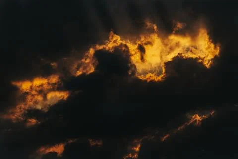Dramatic sky with dark clouds illuminated by golden sunlight creating a str.. Stock Photos
