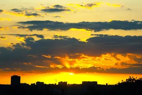 Dramatic sky with dark clouds illuminated by golden sunlight breaking throu.. Stock Photos