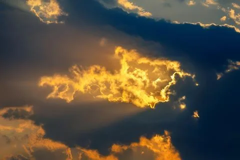 Dramatic sky with dark clouds illuminated by golden sunlight breaking throu.. Stock Photos