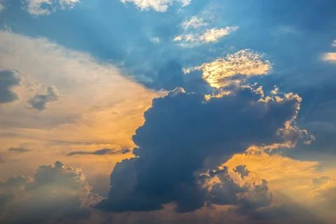 Dramatic sky with dark clouds illuminated by golden sunlight breaking throu.. Stock Photos