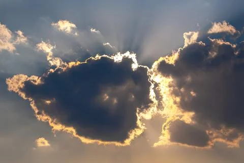Dramatic sky with dark clouds illuminated by golden sunlight breaking throu.. Stock Photos