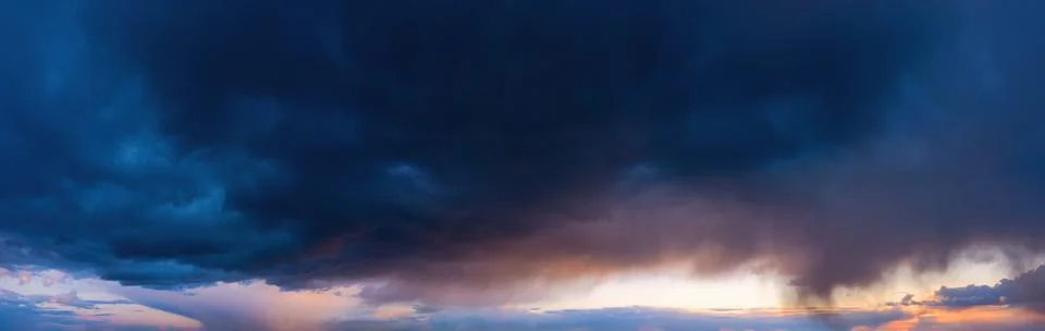 Dramatic sky with dark rainy clouds at sunset. Stock Photos