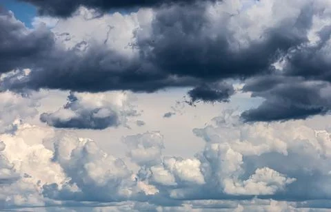 Dramatic sky with dark storm clouds gathering over bright cumulus formations Stock Photos