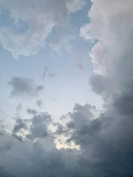 Dramatic sky with dark storm clouds gathering against a pale blue expanse Stock Photos