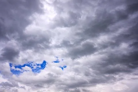 Dramatic sky with dark storm clouds and small blue sky patches visible 스톡 사진
