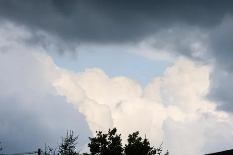 Dramatic sky with dark storm clouds parting to reveal bright cumulus formatio Foto stock