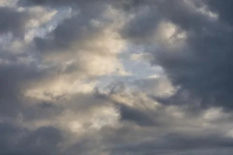 Dramatic sky with dark storm clouds and patches of sunlight breaking through Stock Photos