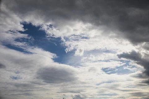 Dramatic sky with dark storm clouds contrasting against patches of bright b.. Stock Photos