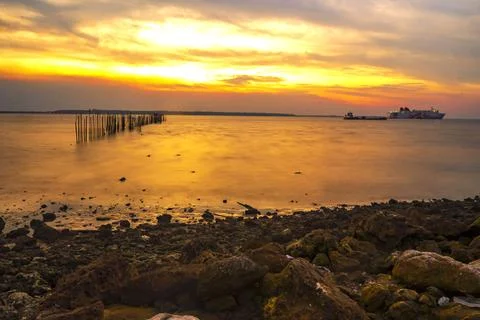 Dramatic sky during sunset with rocks and boats foreground in Bangkalan, Madu Stock-Fotos