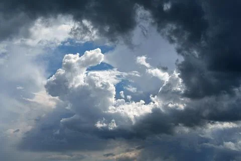 A dramatic sky filled with dark storm clouds illuminated by bright sunlight Stock Photos