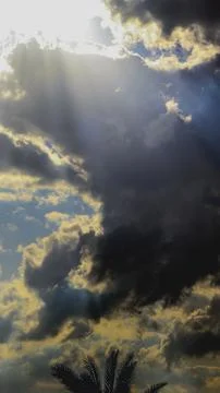 Dramatic sky filled with dark, textured storm clouds pierced by bright sunbeams Stock Photos