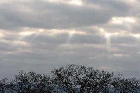 A dramatic sky illuminated by low sunlight through thick, layered clouds, c.. Stock Photos
