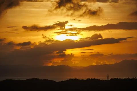 Dramatic sky with layered clouds illuminated by warm orange and yellow hues a Stock Photos