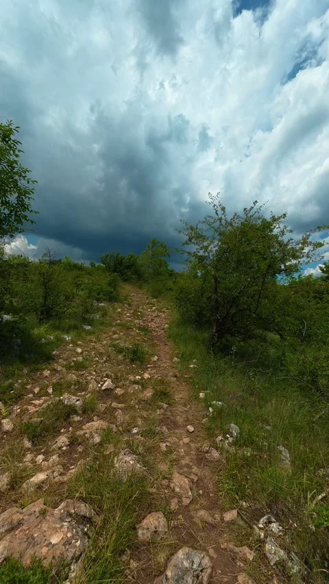 Dramatic sky looms above a rugged, rocky trail. Kozji Kamen area, Vertical 스톡 동영상 341881559