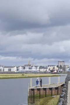 Dramatic sky looms over calm water and distant cityscape 库存照片