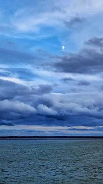 Dramatic Sky with Moon over Calm Sea Horizon Stock Photos
