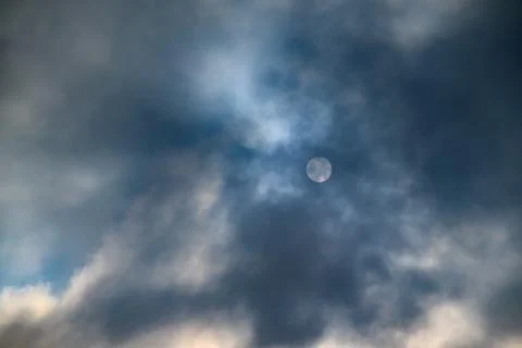 Dramatic sky with moon partially hidden by clouds 库存照片