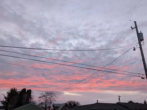 Dramatic sky with orange, white, and blue clouds above rooftops Stock-Fotos