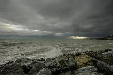 Dramatic sky over the black sea with waves, clouds and stones Stock Photos