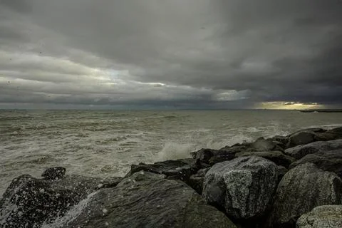 Dramatic sky over the black sea with waves, clouds and stones Stock Photos