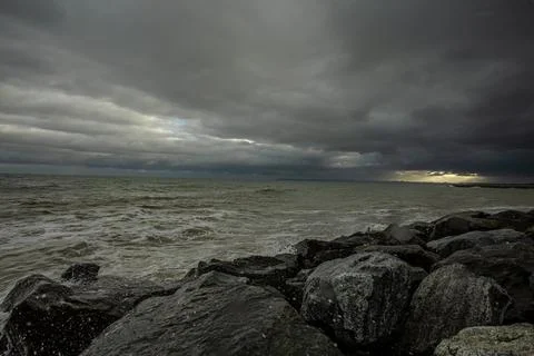 Dramatic sky over the black sea with waves, clouds and stones Stock Photos
