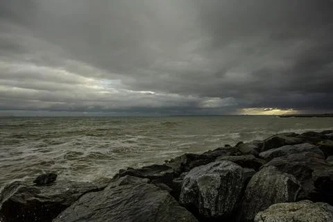 Dramatic sky over the black sea with waves, clouds and stones Stock Photos