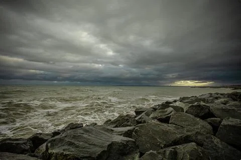 Dramatic sky over the black sea with waves, clouds and stones Stock Photos