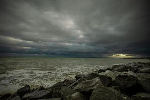 Dramatic sky over the black sea with waves, clouds and stones Stock Photos