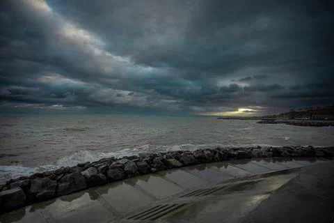 Dramatic sky over the black sea with waves, clouds and stones Stock Photos